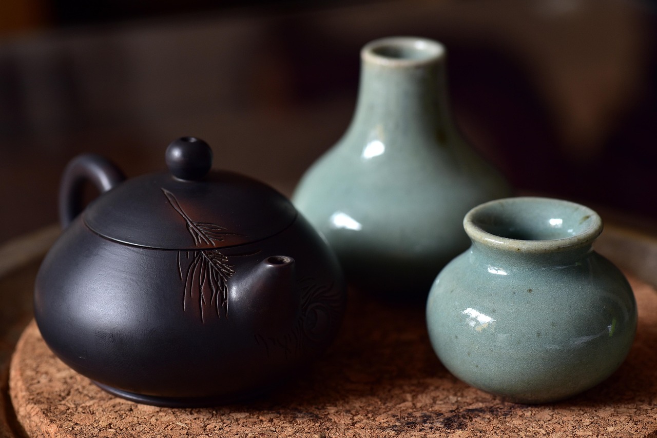A porcelain teapot and two decorative pieces placed on a table